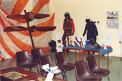 Panoramica della Mostra Fotografica raffigurante l'equipaggiamento dei piloti A.M., le eliche, le sedie per la visione dei filmati ed i tavoli con pannelli strumenti